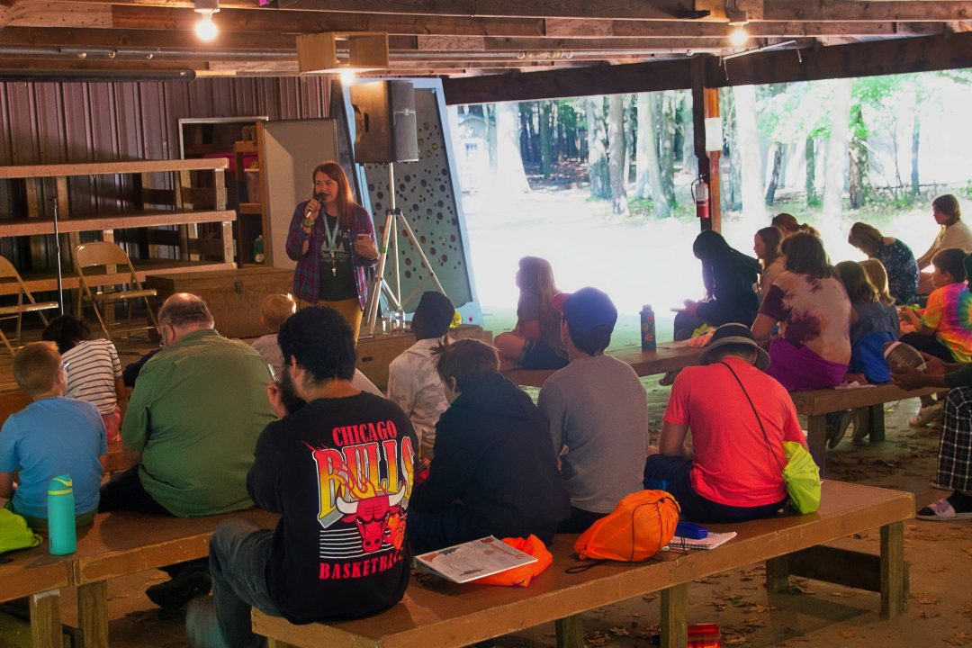 adult volunteer talks with campers and counselors in the pavilion