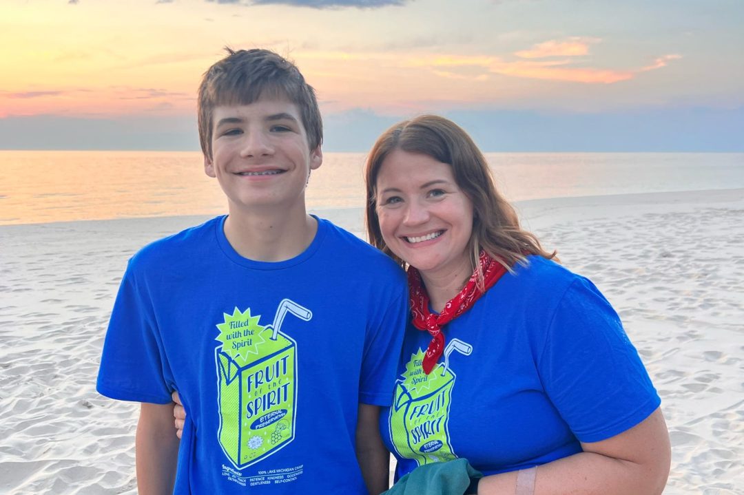 tall teen boy and his mom on the beach near sunset