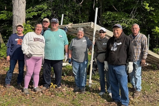 8 people smiling in a woodsy setting