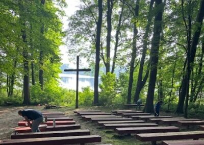 outdoor bench seating overlooking woods, lake and cross