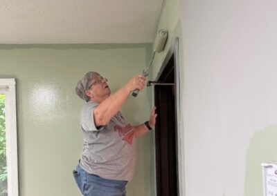 volunteer painting a wall above a door